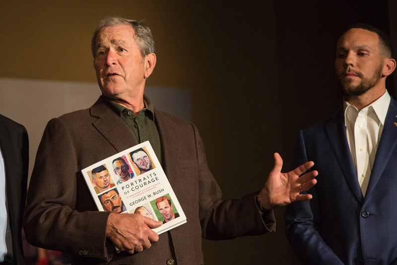 Former US President George W. Bush holds up a print copy of his "Portraits of Courage" painting exhibit as he stands next to one of the veterans featured in the exhibit, Johnnie Yellock, at a press preview at the George W. Bush Presidential Library and Museum in Dallas, Texas, on February 28, 2017. Former US president George W. Bush released a book featuring a series of 66 portraits of wounded or traumatized veterans he had met who served in the US military in Iraq or Afghanistan following the attacks on September 11, 2001. / AFP / Laura BUCKMAN / RESTRICTED TO EDITORIAL USE - MANDATORY MENTION OF THE ARTIST UPON PUBLICATION - TO ILLUSTRATE THE EVENT AS SPECIFIED IN THE CAPTION (Photo credit should read LAURA BUCKMAN/AFP/Getty Images)