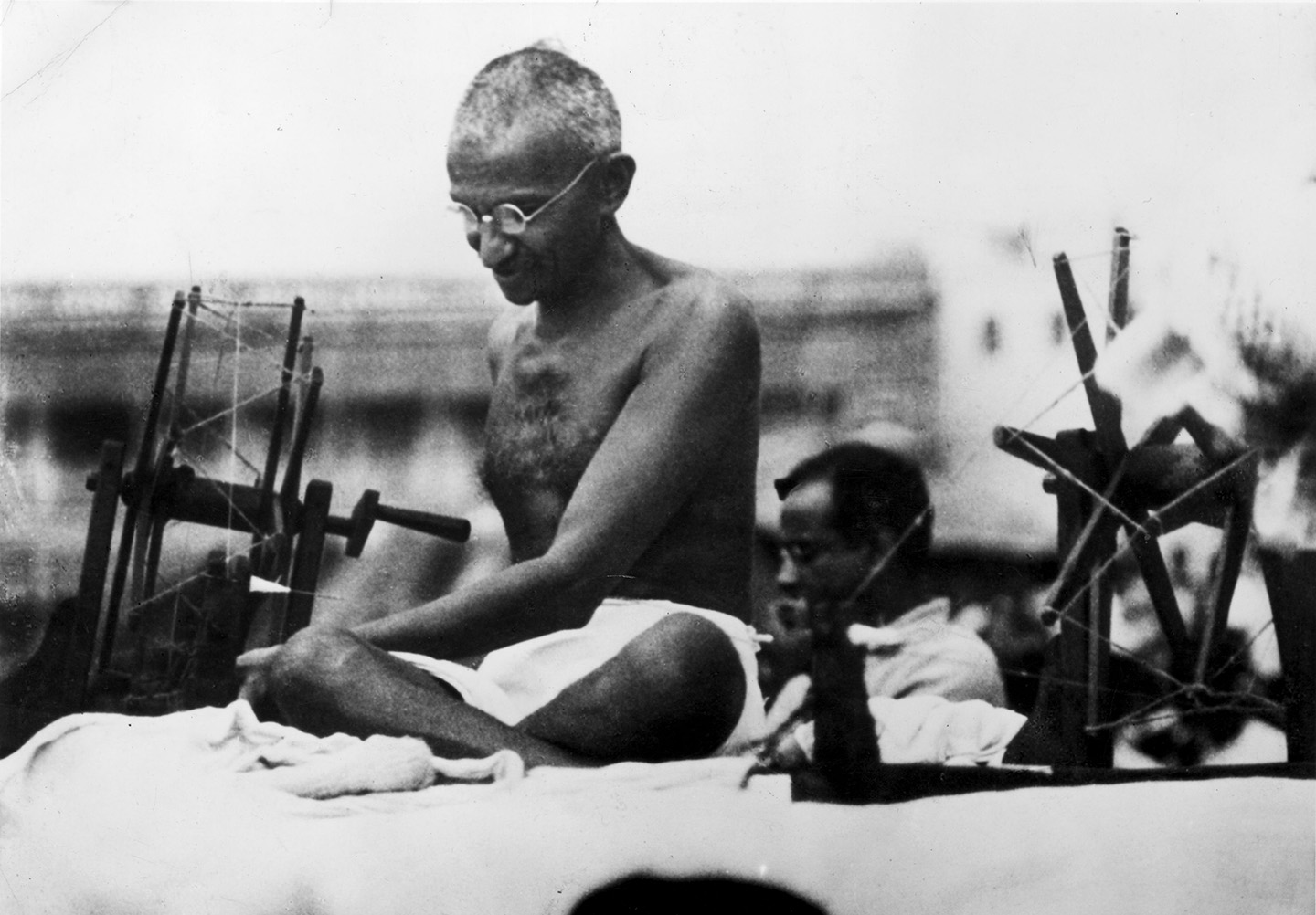 Indian Nationalist leader Mahatma Gandhi (Mohandas Karamchand Gandhi, 1869 - 1948) at a spinning wheel during a 'Charlea' demonstration in Mirzapur, Uttar Pradesh.  (Hulton Archive/Getty Images)