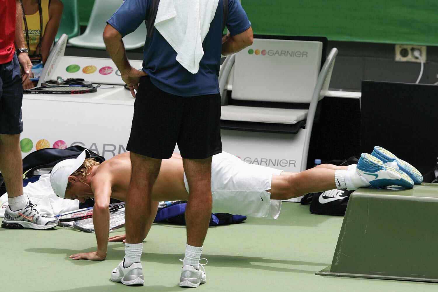 A man performing push-ups on a tennis court.