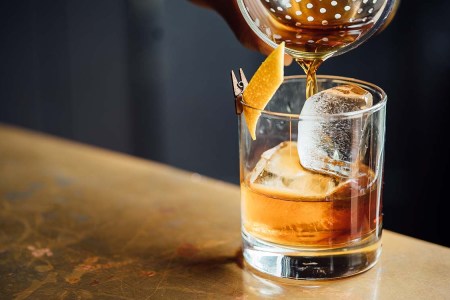 Straining a cocktail over ice into a rocks glass