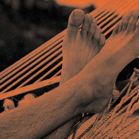 A pair of feet resting on a hammock.