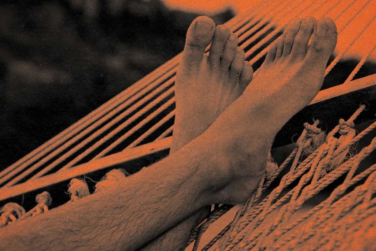 A pair of feet resting on a hammock.