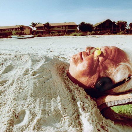 Senior Man Buried in Sand at the Beach - stock photo