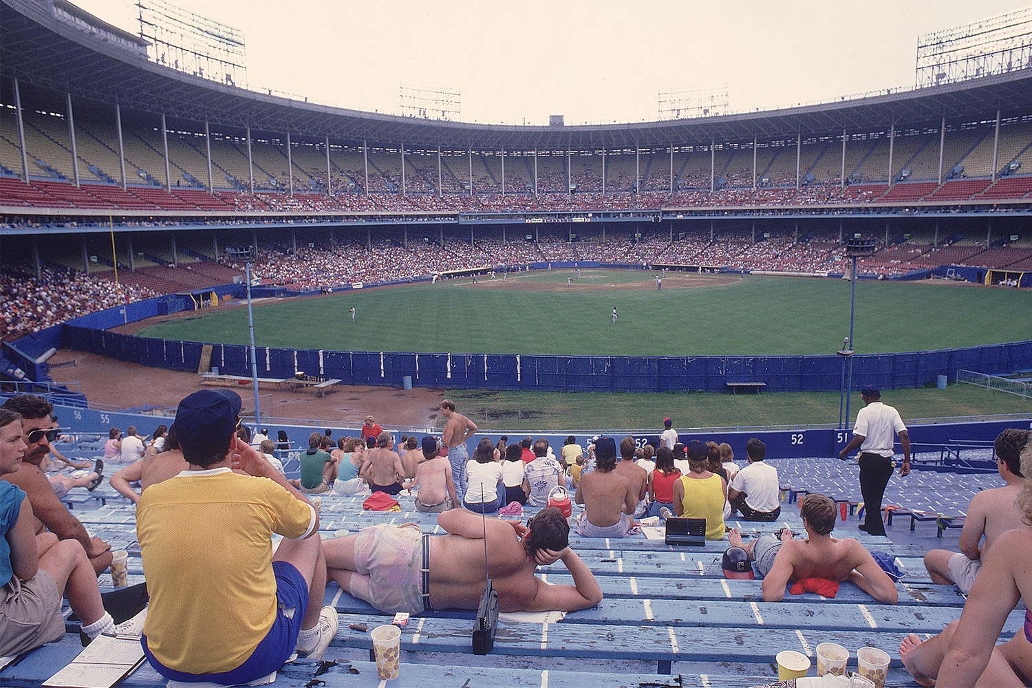Fans lounging around a somewhat empty bleachers section at a baseball game.