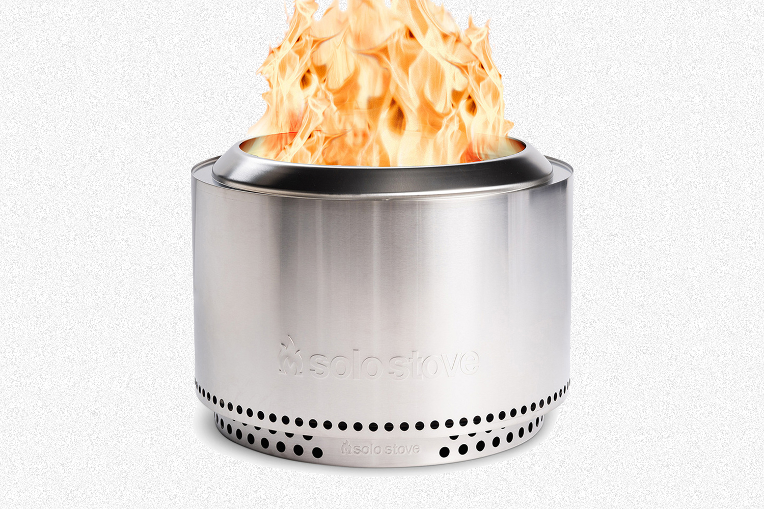 The Solo Stove Yukon fire pit and stand with a fire raging inside on a grey background. The stainless steel fire pit is on sale for a limited time.