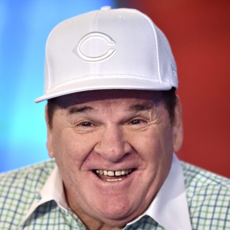 Pete Rose visits the Fox Business Network Studios wearing a white Cincinnati Reds hat and a green checker shirt with a white collar