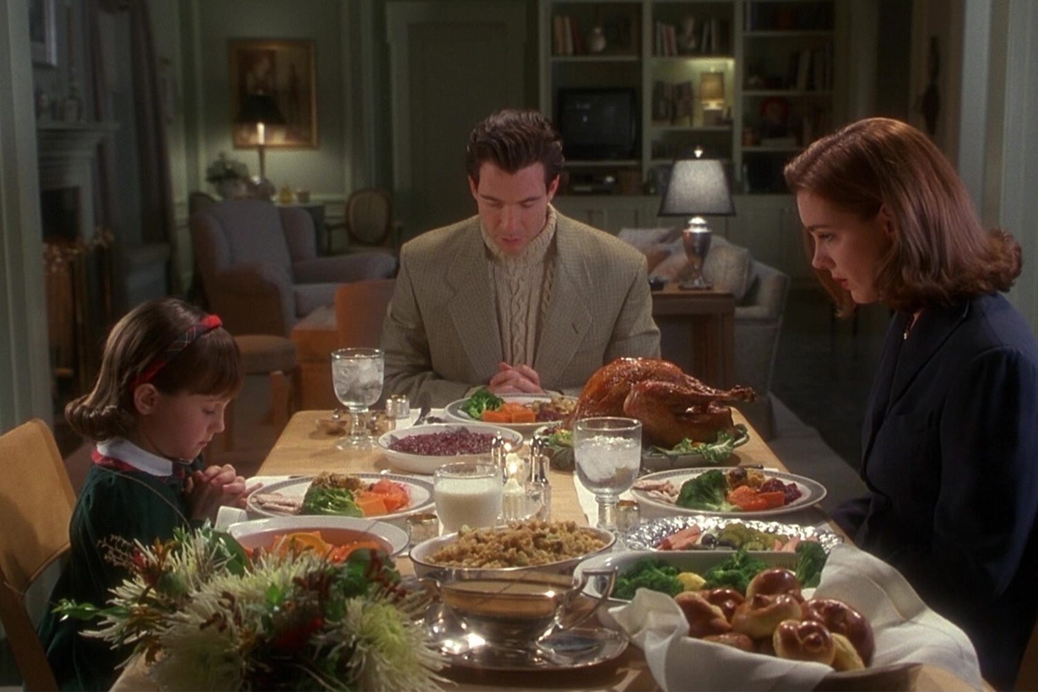 Mara Wilson, Dylan McDermott and Elizabeth Perkins sitting down for Thanksgiving dinner in the 1994 movie Miracle on 34th Street