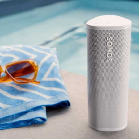 A Sonos Roam near a pool, towel and sunglasses. Sonos gear that is refurbished often nets you an extra discount.