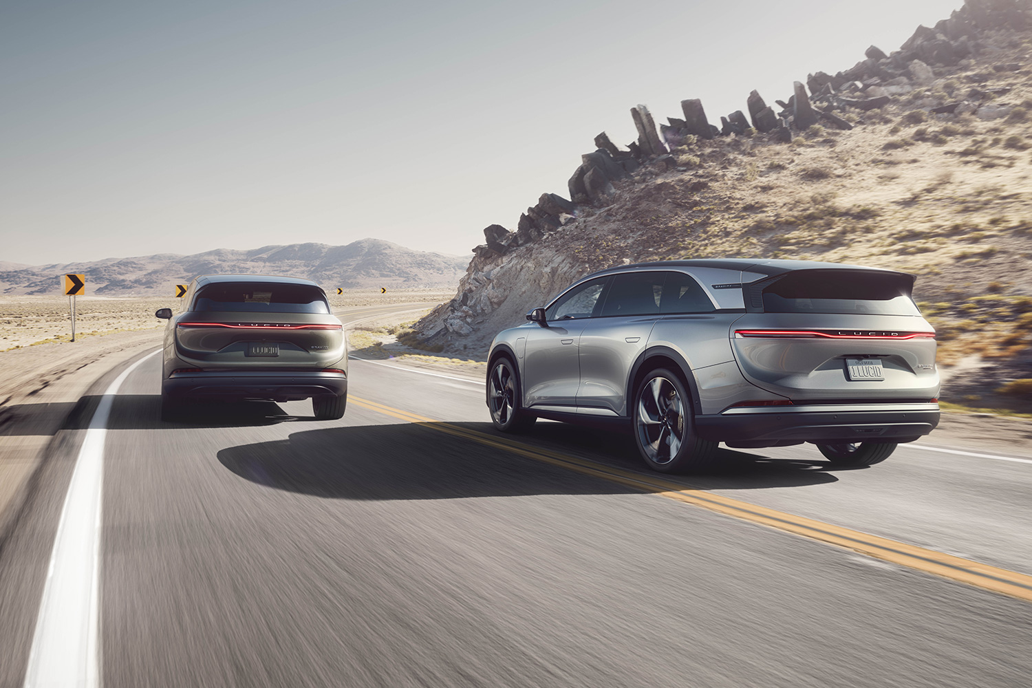 Two Lucid SUVs driving on a road in the desert