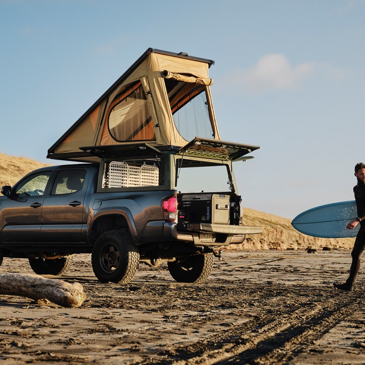 The Super Pacific X1, a truck canopy camper, in the bed of a pickup sitting on the beach