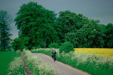 A man cycles down a countryside road.