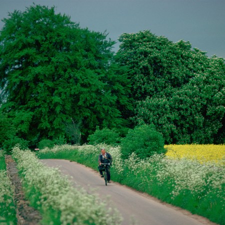 A man cycles down a countryside road.