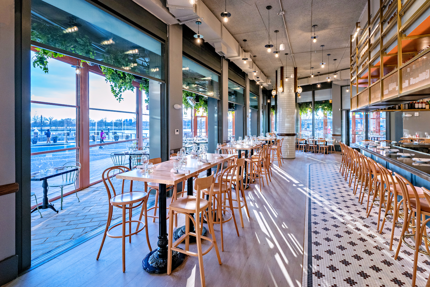 a light filled wine bar with a black and white tiled floor and wall of windows