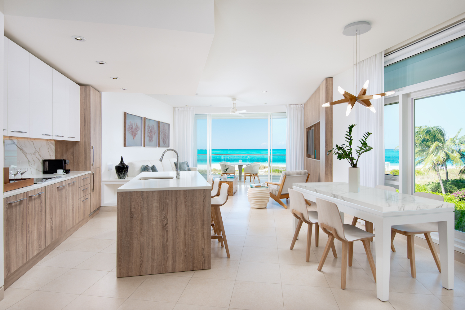 a bright suite with light wood and white walls overlooking the blue ocean and green palm trees