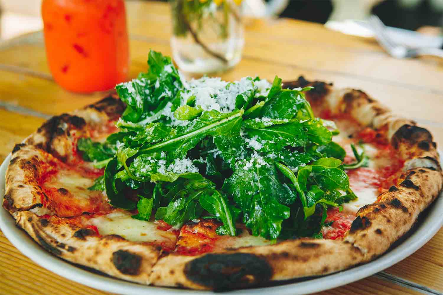 A pizza with arugula and a few colorful cocktails at Flora Farms