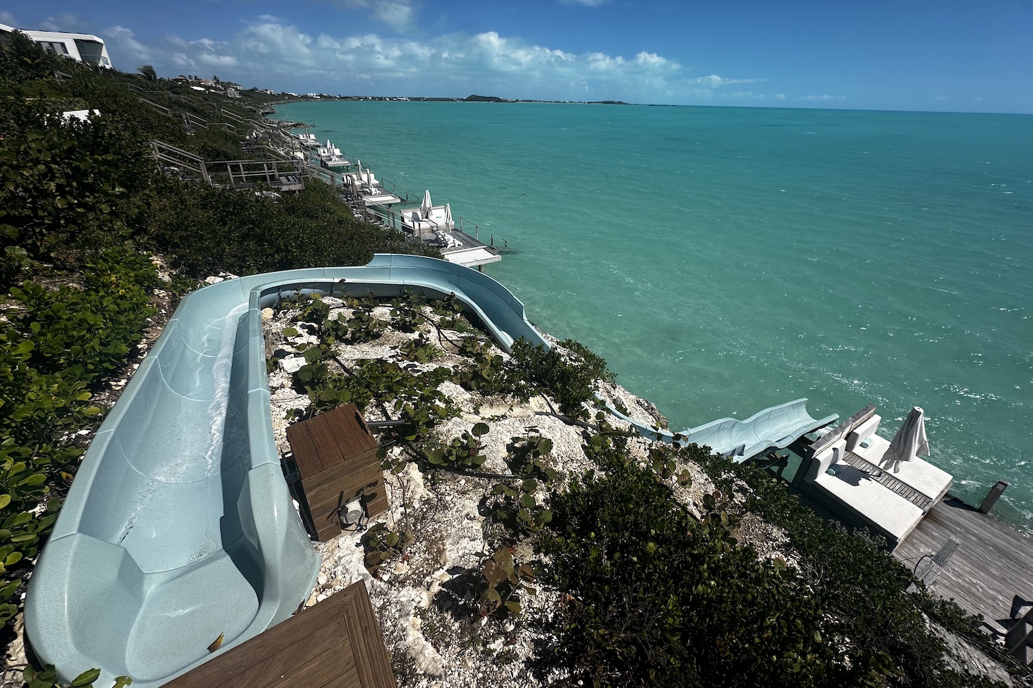 a water slide snaking down a cliff into the blue caribbean sea