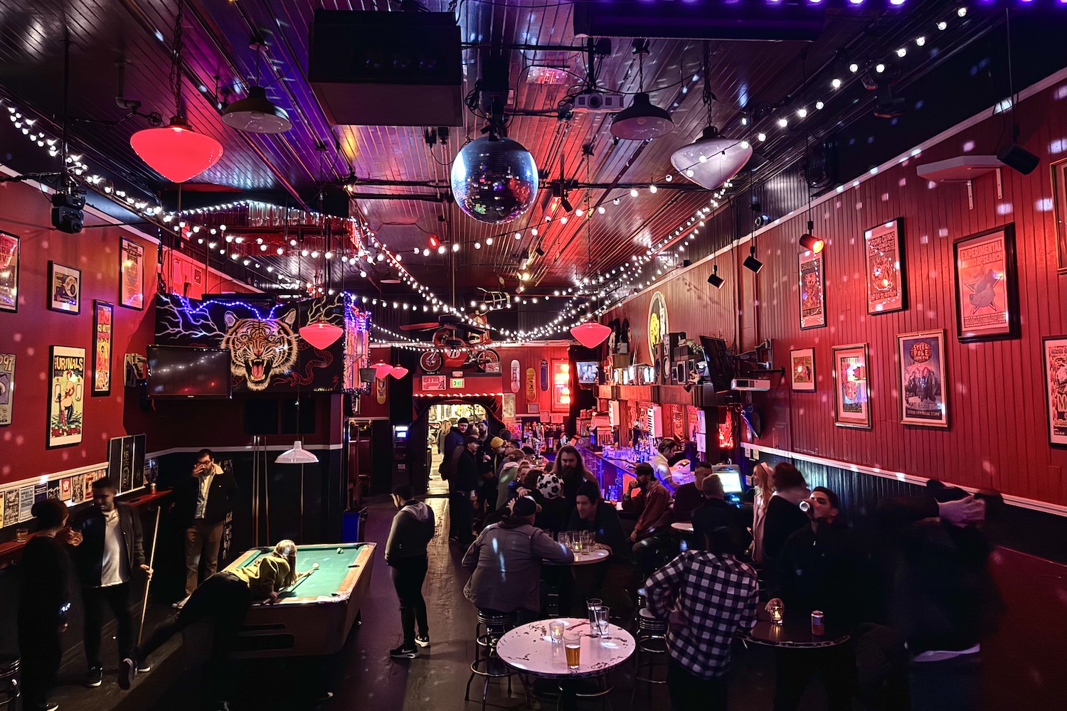 Interior of Kilowatt, with string lights across the ceiling and people sitting in chairs with drinks.