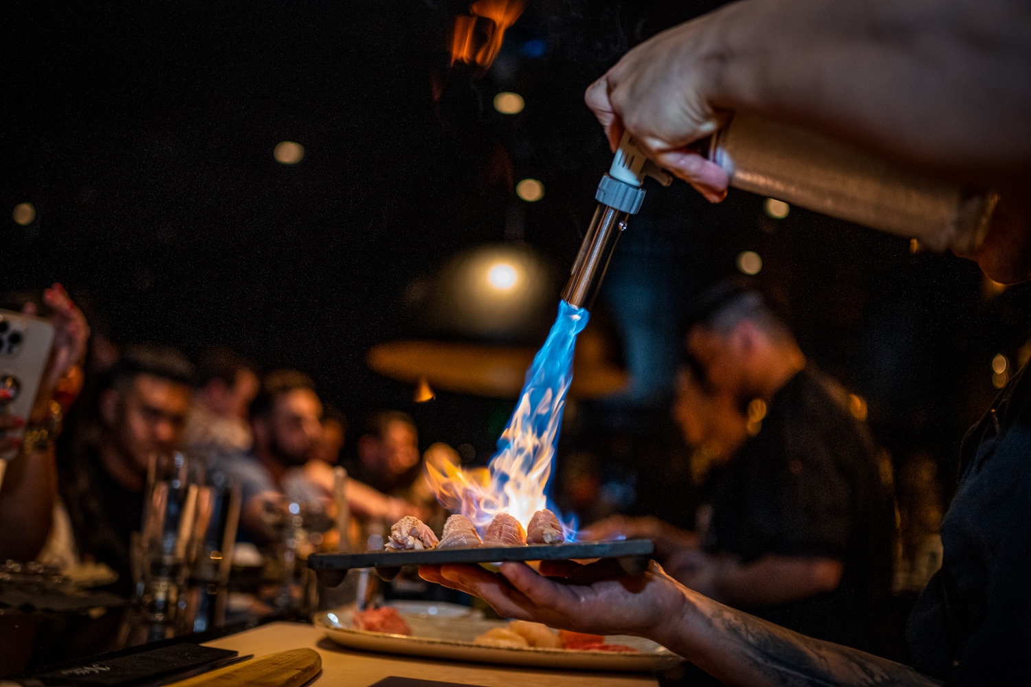 flaming sushi plate, people sitting watching