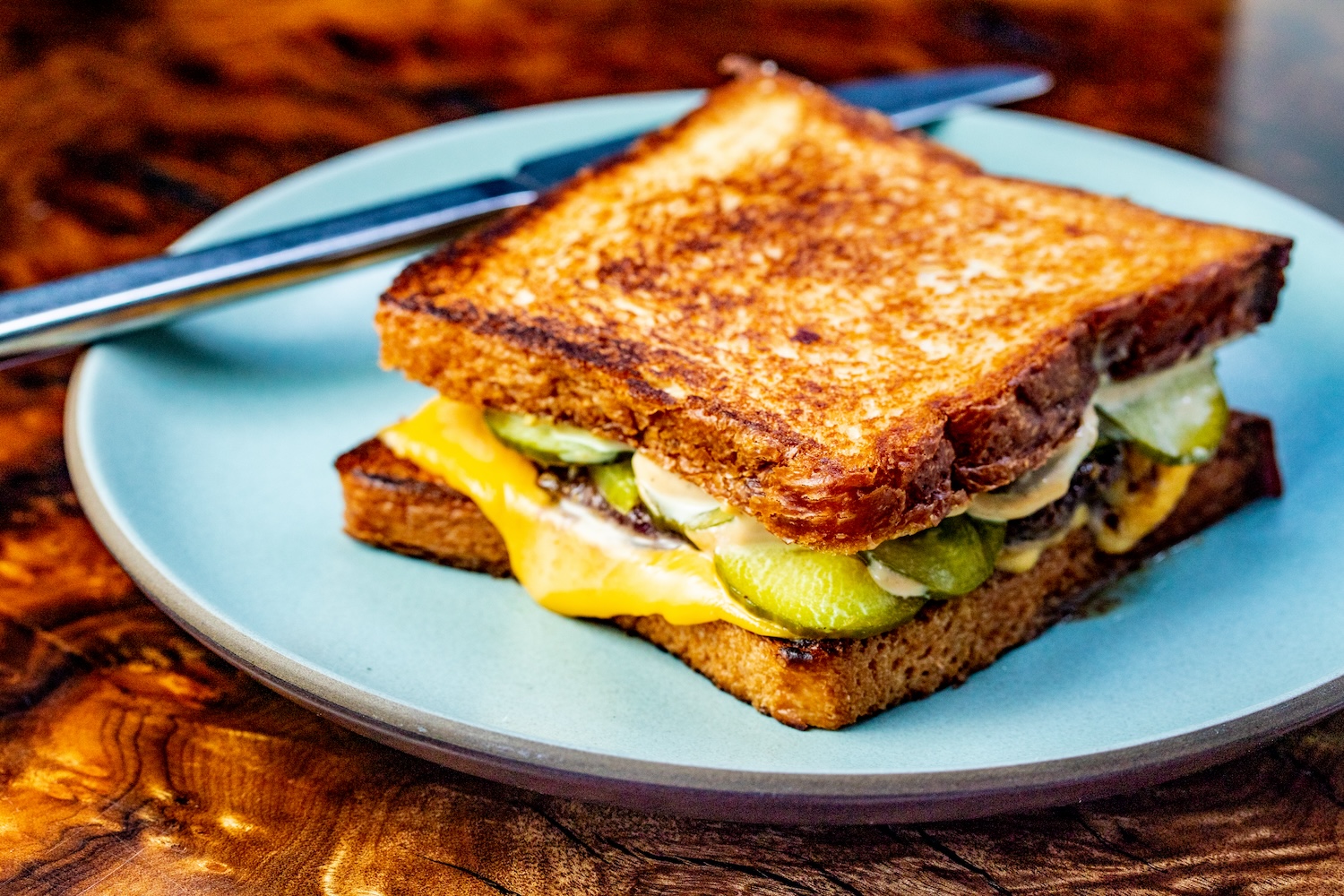 grilled cheese sandwich with pickles on a blue plate