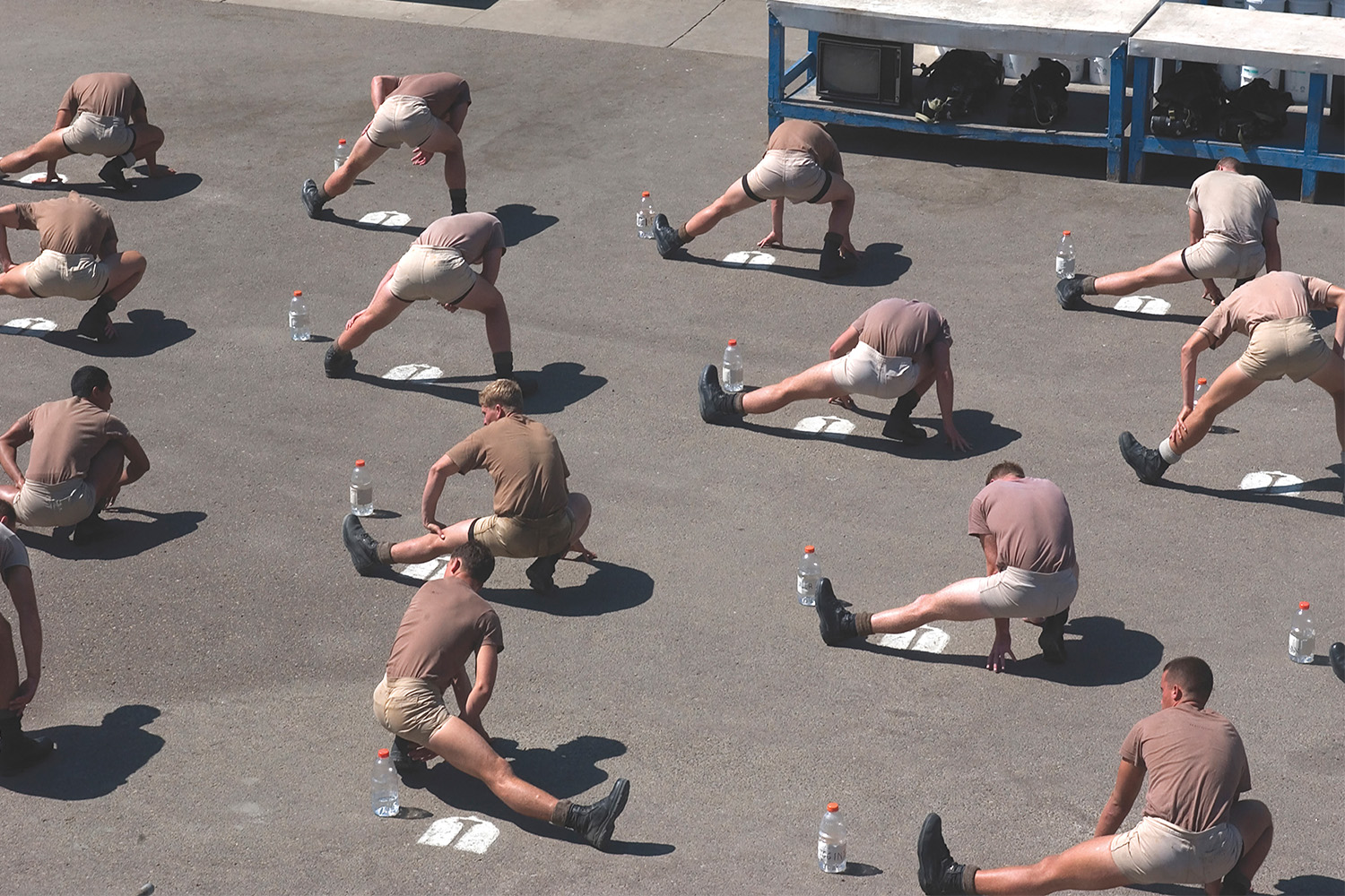 A group of men stretching on the ground. The frog pose is an ideal yoga pose and stretch for people who sit all day.