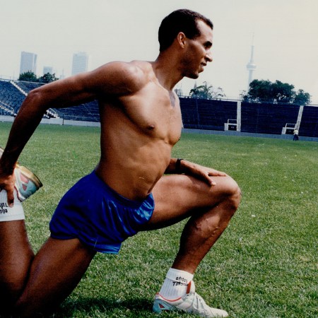 A fit man stretching on a turf field.
