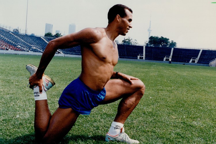 A fit man stretching on a turf field.