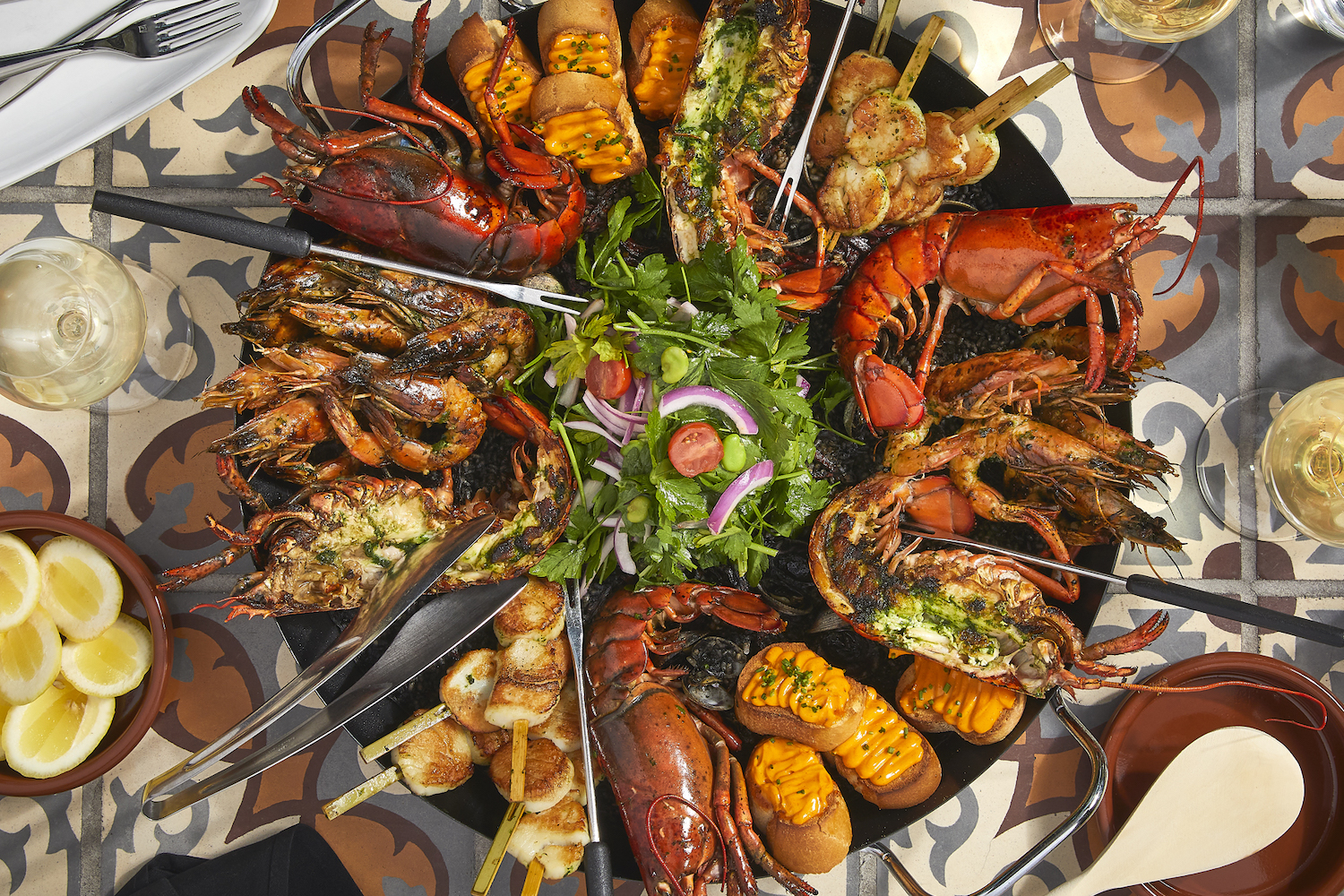 a huge plate of seafood paella with lobster, shrimp, scallops and black rice