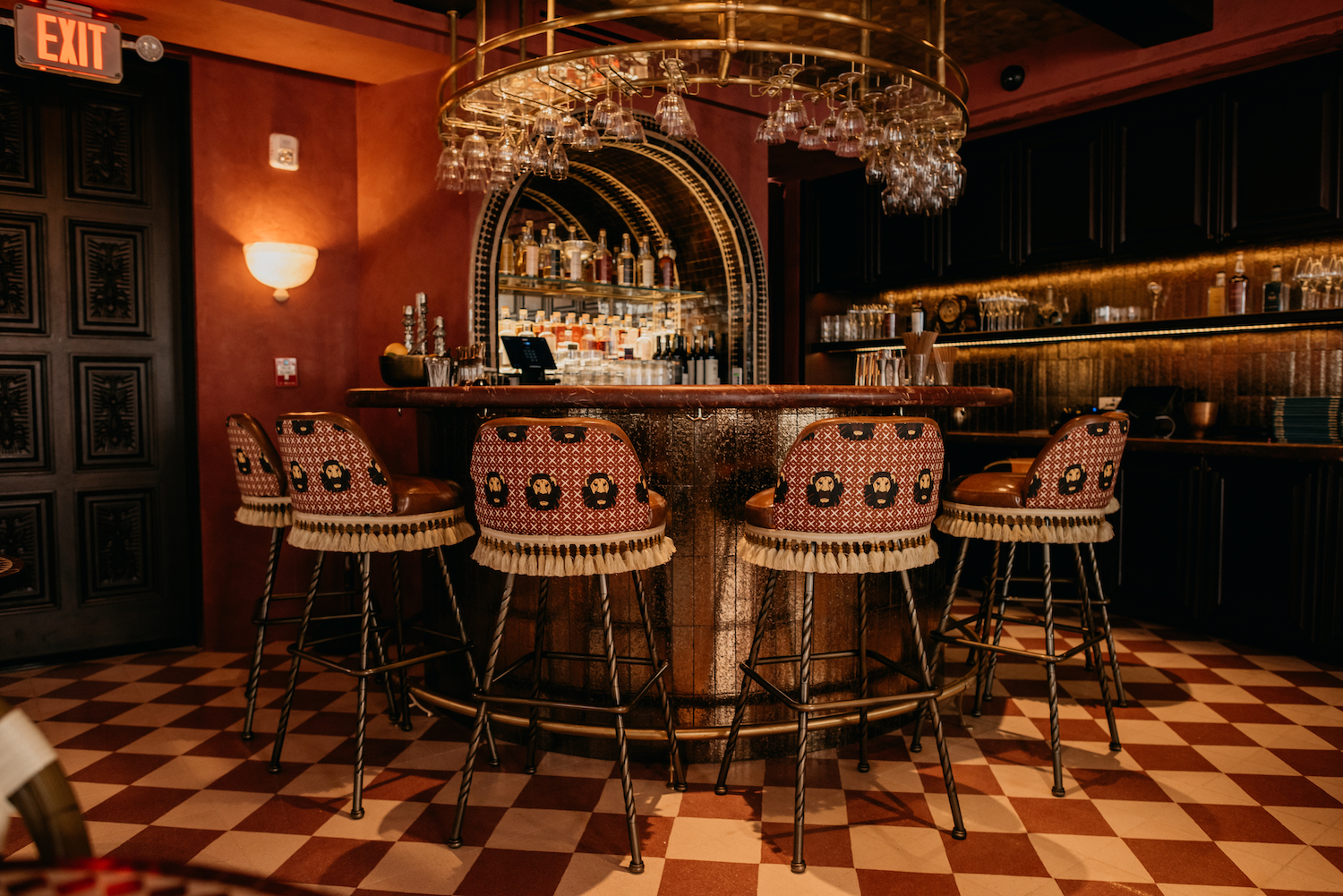 a bar with a red and white tiled floor with tasseled chairs