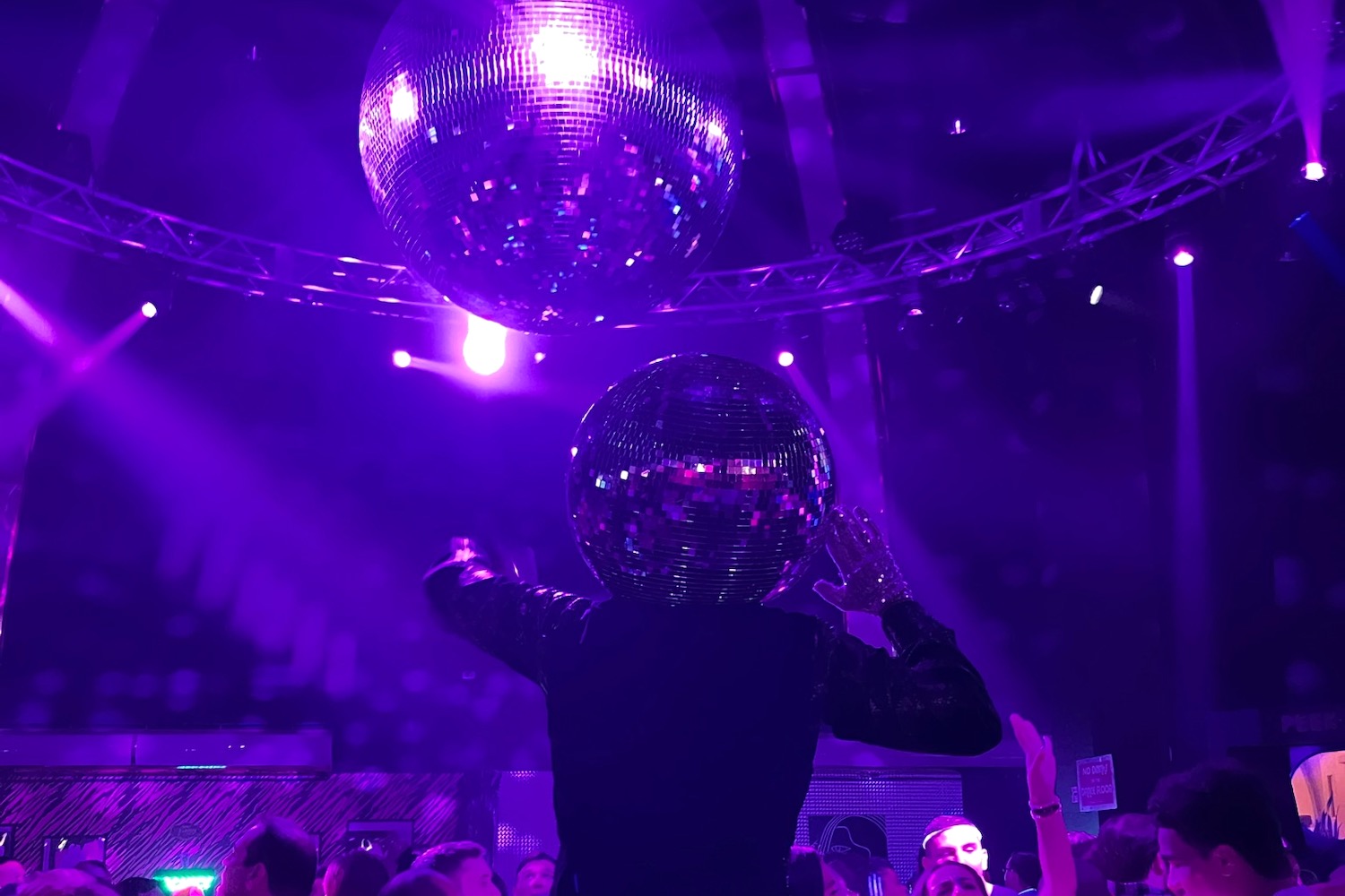 a man wearing a disco ball on his head in a dance club with a disco ball