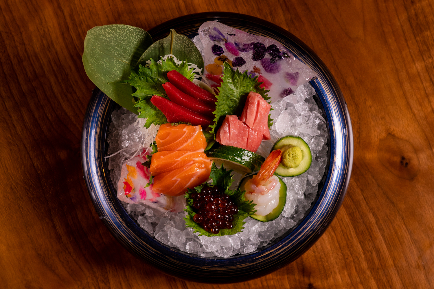 a bowl of sashimi with cucumber slices and shiso