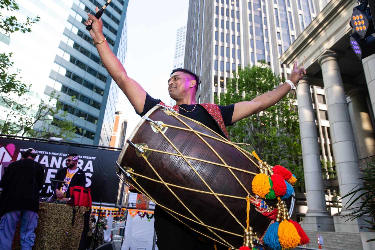 a man playing a giant drum outside with tassels hanging from it