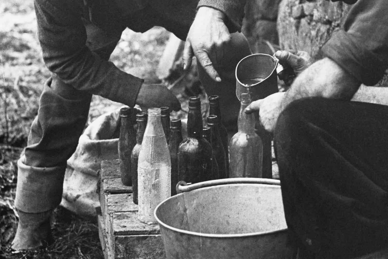 From 1952: poitin makers are still active in remote parts of Ireland despite official dissaproval. A local 'specialist' in the illegal liquor shows how it is made. The poteen makers store the liquid into old lemonade or medicine bottles.