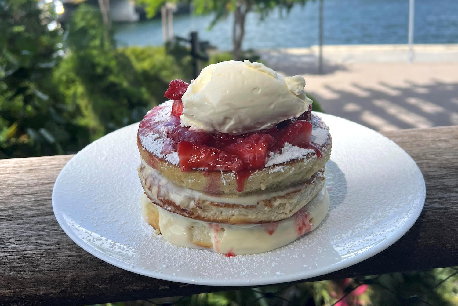 a stack of pancakes on a white plate with strawberry compote and sweet mascarpone