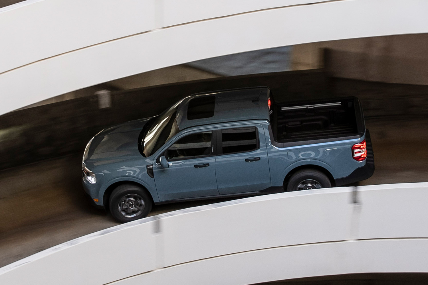 A Ford Maverick Hybrid driving down a parking garage ramp. We dig into why this pickup truck is being ignored by most Americans, despite it being near-perfect.