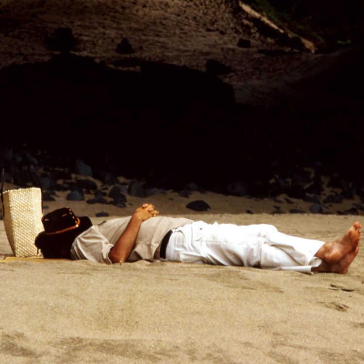 A man resting on a beach. Not tracking my sleep stats is one of my seven healthiest habits.