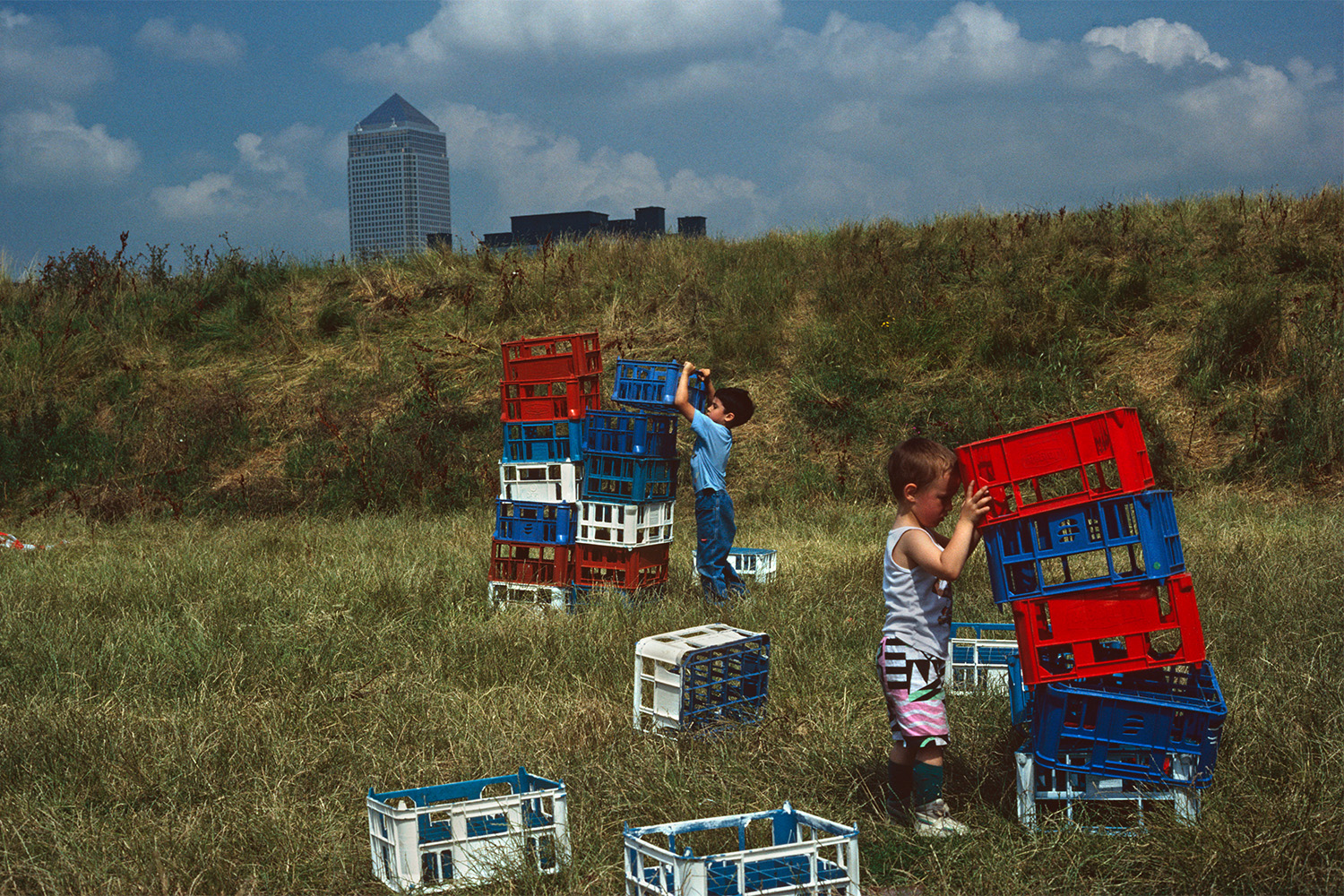A pair of young boys playing with crates in a field.