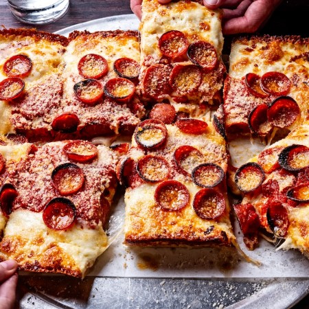 two hands reaching for slices of detroit-style pepperoni pizza