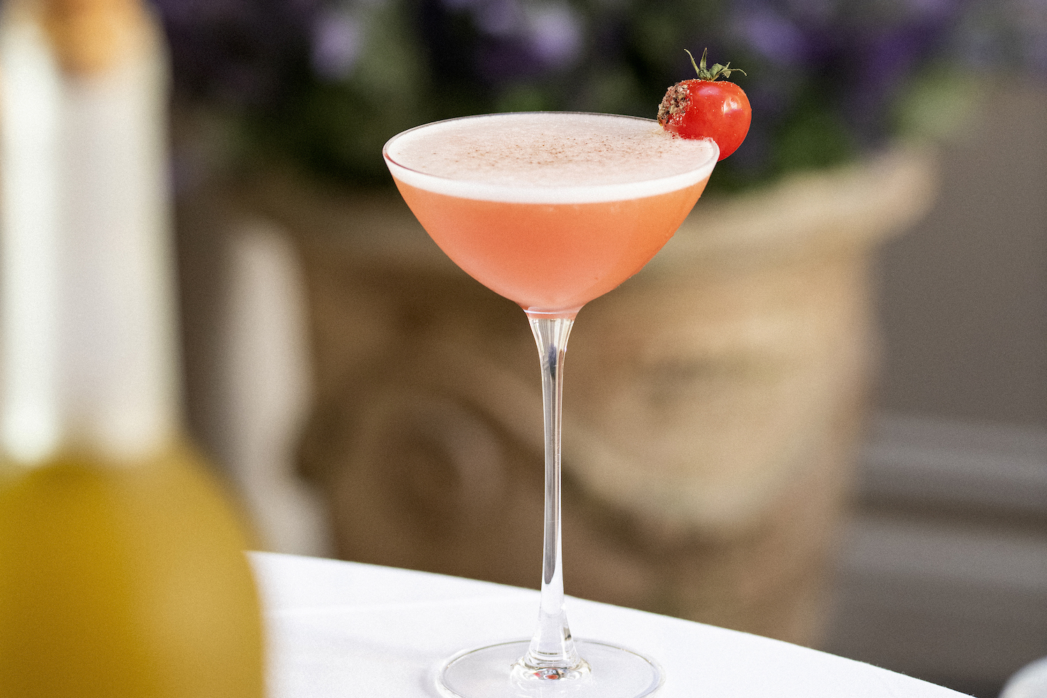 a pink tomato martini in a coupe glass on a white table