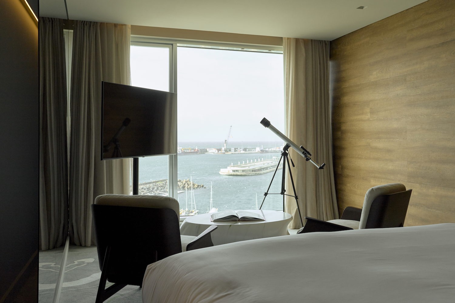 a hotel room with a telescope and a window overlooking a marina