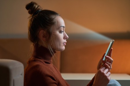 A woman using her selfie camera on her phone to scan her face for facial recognition security measures