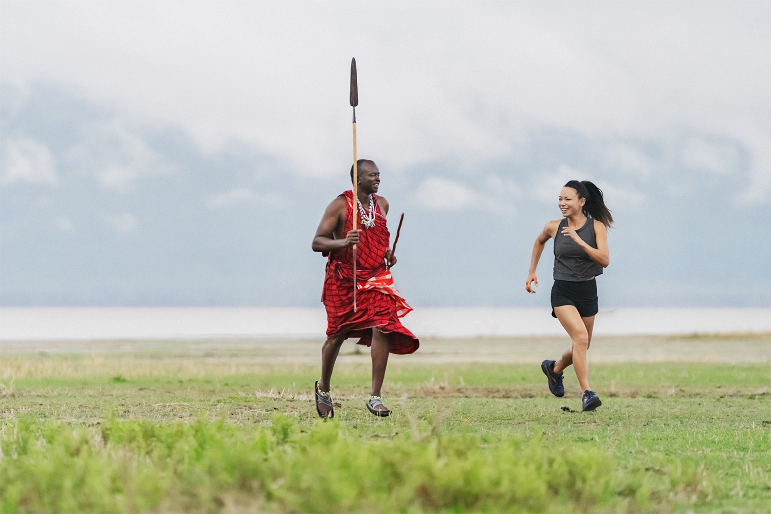 A Maasai warrior running with a tourist.