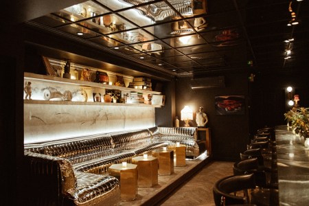 a dark bar with a mirrored leather banquet and mirrored ceiling