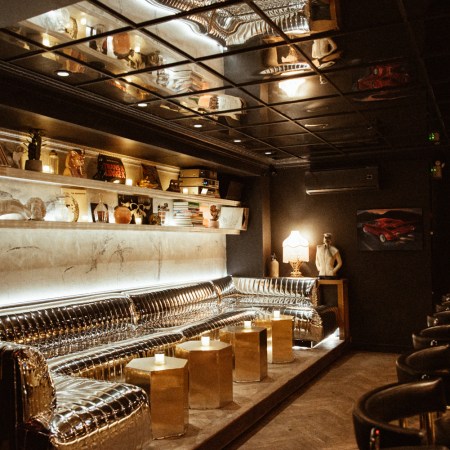 a dark bar with a mirrored leather banquet and mirrored ceiling