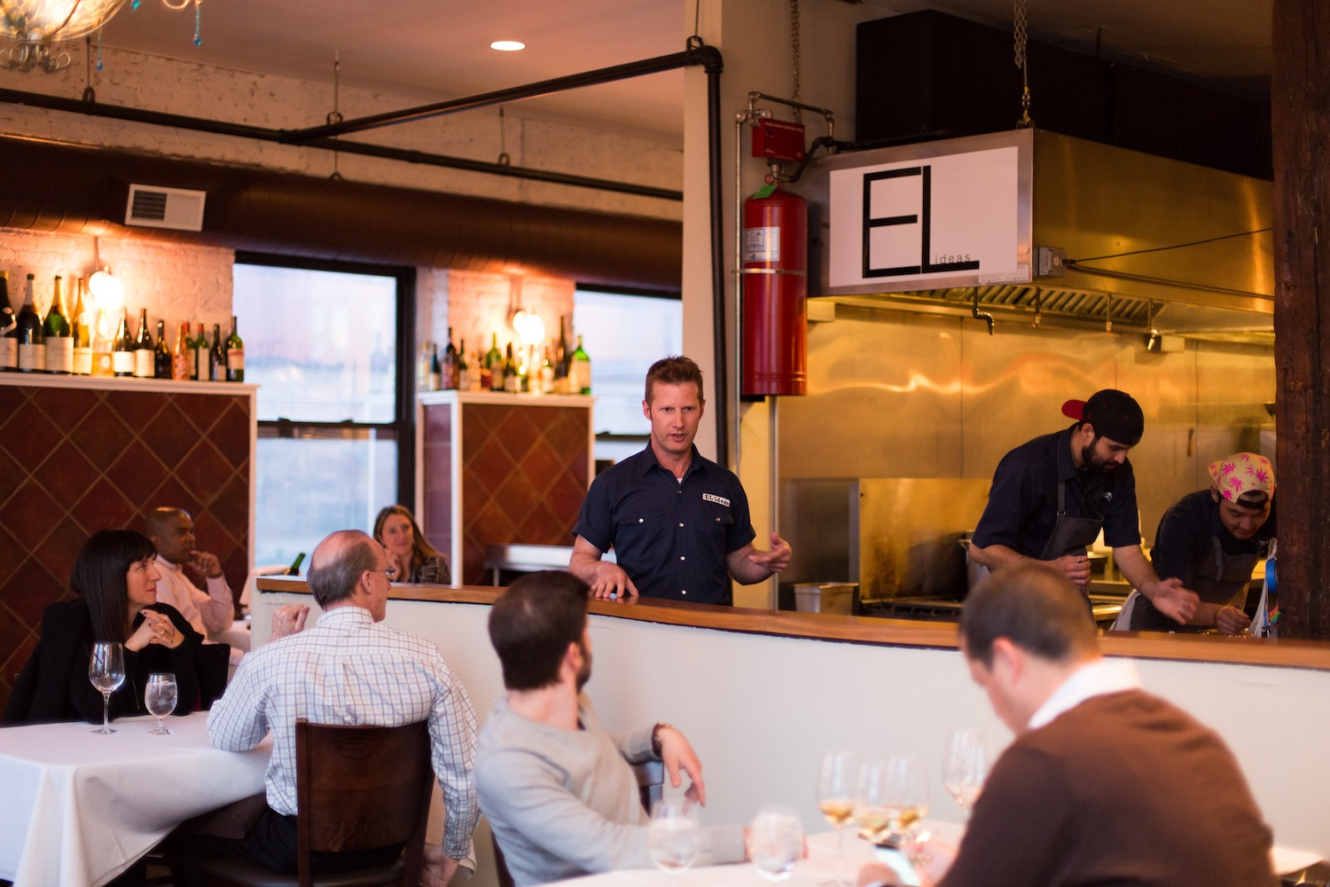 Man standing in a restaurant and people at tables around him are looking at him.