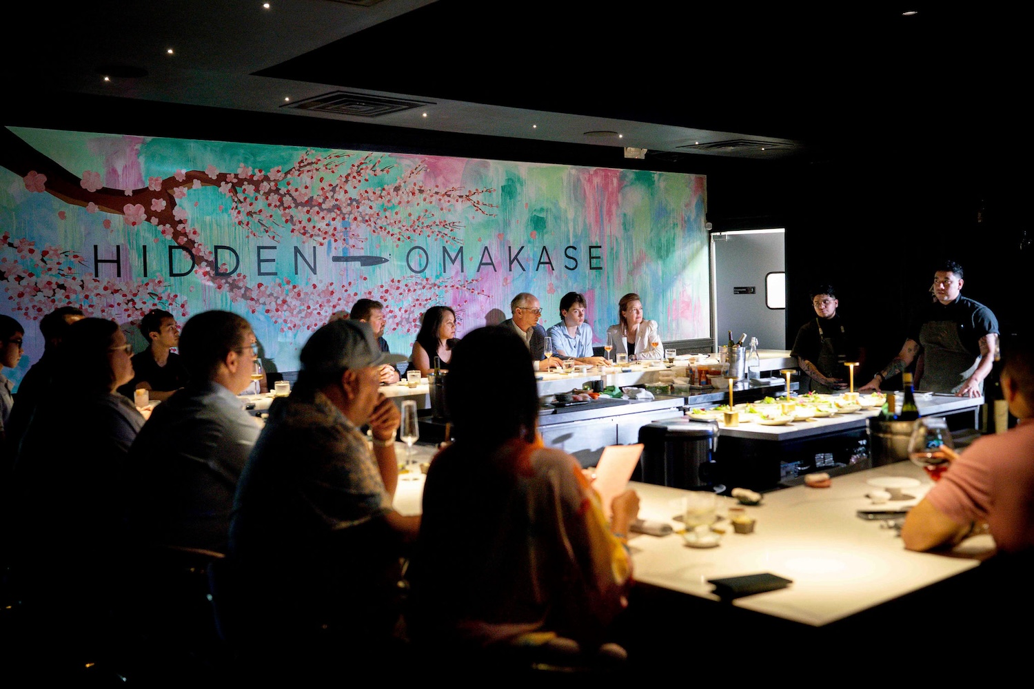 People sitting at a U-shaped table watching a man standing at a table in the center