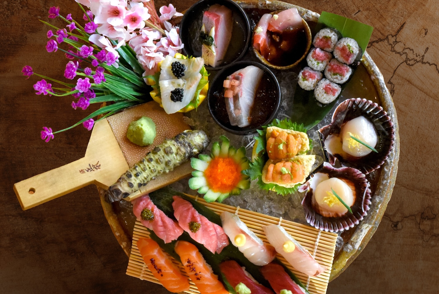 Various kind of sushi arranged in a circular tray decorated with small white, purple and pink flowers