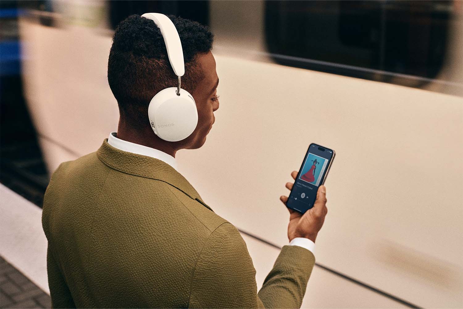 A man wearing the Sonos Ace headphones and listening to his phone