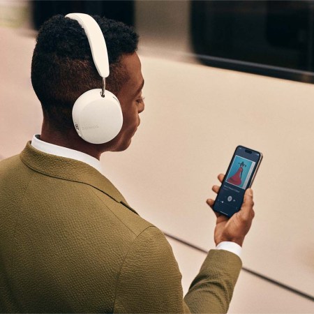 A man wearing the Sonos Ace headphones and listening to his phone