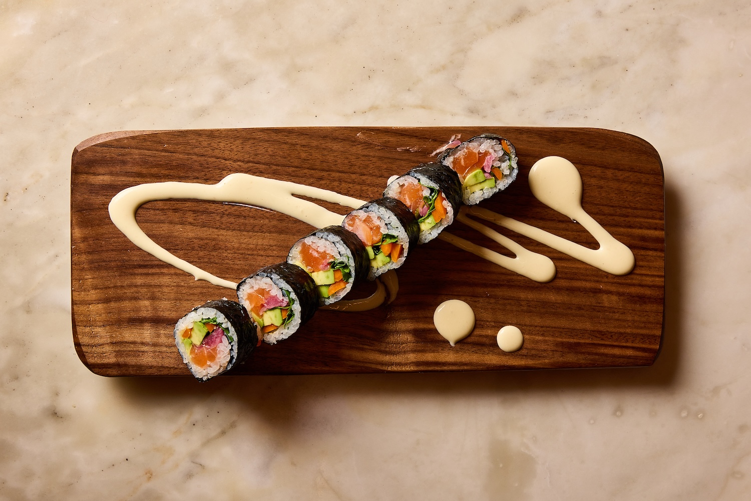 Plated sushi rolls on a board with sauce