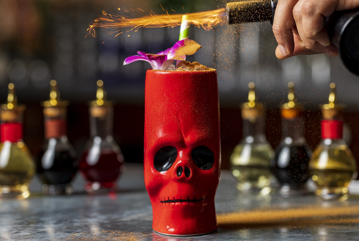 Red skull tiki mug with hibiscus flower on top that is lit